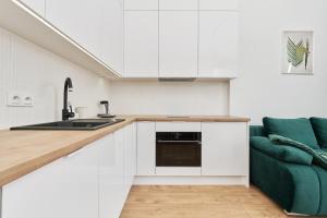 a kitchen with white cabinets and a green couch at Apartment By the Oder River Wrocław by Renters in Wrocław