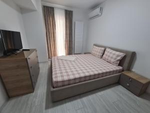 ein kleines Schlafzimmer mit einem Bett und einem TV in der Unterkunft Apartament Moghioros Park Residence DUM1 in Bukarest