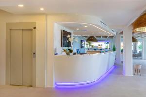 un vestíbulo con un mostrador blanco con luces moradas en Hotel Maysi, en Playa de Migjorn