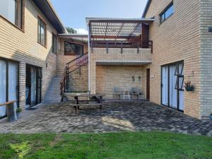 a patio with a bench next to a brick building at Pladda in Plett in Plettenberg Bay