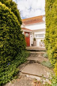 a house with a red door between two bushes at Raddicombe Lodge, room only accommodation in Brixham