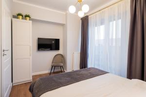 une chambre avec un lit, une télévision et une chaise dans l'établissement Golden Mirage Sunset Apartment, à Mamaia