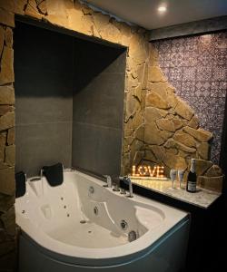 a bath tub in a bathroom with a stone wall at Aparta suite la nuit in Calafell