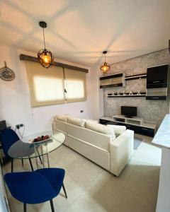 uma sala de estar com um sofá branco e cadeiras azuis em Aparta suite la nuit em Calafell