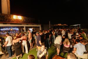 una folla di persone che di notte si alzano davanti a un bar di Athens Hawks ad Atene