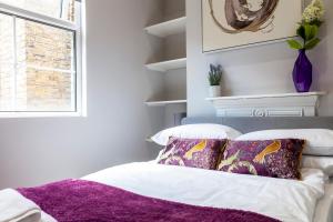 een slaapkamer met een paarse deken op een bed bij West Kensington in Londen
