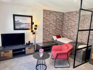 a living room with a red chair and a television at City Appartements Arnstadt in Arnstadt