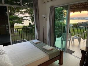 a bedroom with a bed and a balcony with a view at My Beach Villa in Port Dickson