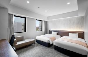a bedroom with two beds and a chair and two windows at Daiwa Roynet Hotel Sapporo Nakajima Koen in Sapporo