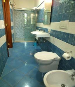 bagno piastrellato blu con servizi igienici e lavandino di Agriturismo L'Angela a Borgagne