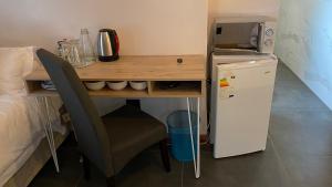 a desk with a chair and a refrigerator in a room at The Chameleon Stay @107 in Centurion
