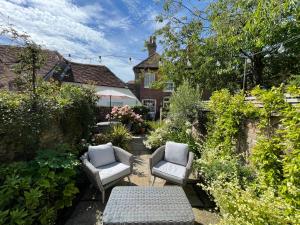 a patio with two chairs and a table in a garden at The Courtyard in Chichester