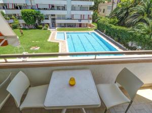 a table and chairs in front of a swimming pool at Clarimar Beach Apartment by Hello Homes Sitges in Sitges