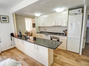 a kitchen with white cabinets and a black counter top at Clarimar Beach Apartment by Hello Homes Sitges in Sitges