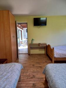 1 dormitorio con 2 camas y TV en la pared en Chata Kurpiowska, en Nowogród