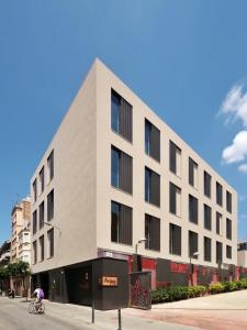 a building on a street with a person riding a bike at Hotel Orangine in Hospitalet de Llobregat