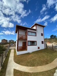 a white house with a balcony on the grass at CHALÉS SÓ COISAS BOAS in Ouro Preto