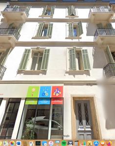 un edificio blanco con ventanas y letreros. en Résidence Montaigne - Luxurious - 350m Palais - LRA Cannes en Cannes