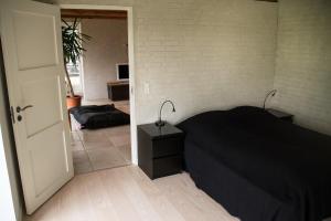 a bedroom with a black bed and a hallway at Øvej 18 Holiday House in Ringsted