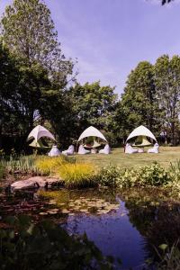 three tents in a field next to a pond at Stirrups Hotel in Bracknell