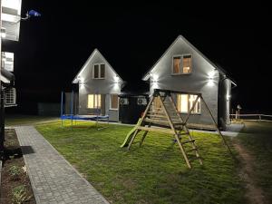 uma casa com um parque infantil no quintal à noite em Domy przy Spokojnej em Jantar