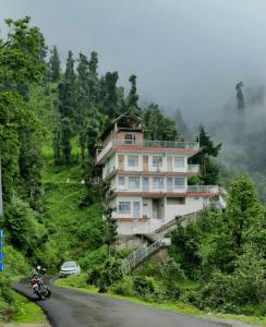 a house on the side of a hill with a motorcycle at FORTUNE HEIGHTS DALHOUSiE in Dalhousie