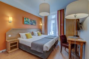a hotel room with a bed and a desk at Hôtel Miléade L'Orangeraie - Menton in Menton