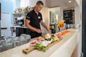 a man standing in a kitchen preparing food at Hôtel Miléade L'Orangeraie - Menton in Menton
