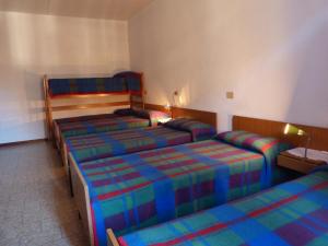 una habitación de hotel con 3 camas en una habitación en Ostello Al Deserto, en Chiavenna