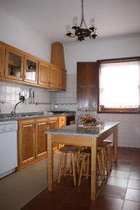 a kitchen with wooden cabinets and a table with stools at Abrigo da Geira House in Campo do Gerês