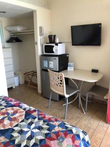 um quarto com uma mesa, uma televisão e uma cama em Starfire Motel em Wildwood