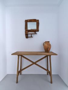 een houten tafel met een vaas erop en een spiegel bij Siora of Paros - Ammiralis & Castelis in Naousa
