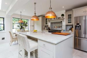 a kitchen with white cabinets and a large kitchen island at Veeve - Curiouser and Curiouser in London