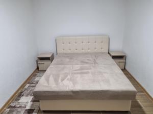 a white bed in a room with two tables at Apartman „Škobić” in Višegrad