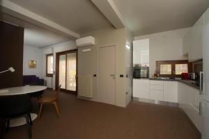 una cucina con armadi bianchi, tavolo e sedie di appartamento Villa del Sole a Desenzano del Garda