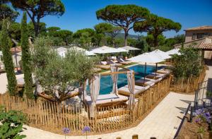 a pool at a resort with lounge chairs and umbrellas at Hôtel L'Escalet in Ramatuelle