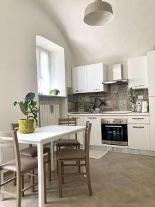 a kitchen with white cabinets and a table and chairs at Nina's House in Pinerolo