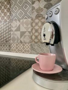 une cafetière avec une tasse rose sur un comptoir dans l'établissement Nina's House, à Pignerol