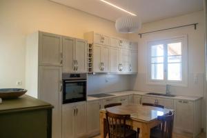 a kitchen with white cabinets and a table and a window at G&N APARTMENT in Messini