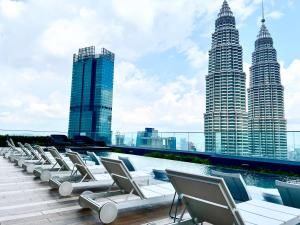 una fila di sedie a sdraio sul tetto di un edificio con edifici alti di Star Residence KLCC By FZB a Kuala Lumpur