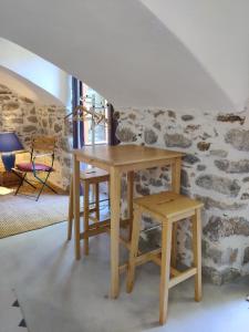 une table en bois et un tabouret dans une chambre avec un mur en pierre dans l'établissement Rendez-vous sous le tilleul, en Cevennes., à Molières-Cavaillac