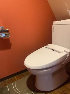 a white toilet in a bathroom with an orange wall at Sakara Gion in Kyoto