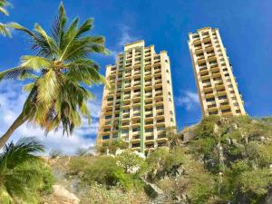 dos edificios altos en la playa con palmeras en Apartamentos Edificio El Peñón del Rodadero!, en Santa Marta