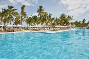 a pool at a resort with chairs and umbrellas at Hotel Riu Jambo - All Inclusive in Nungwi