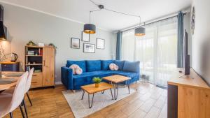 een woonkamer met een blauwe bank en een tafel bij Apartamenty Sun & Snow Gąski in Gąski