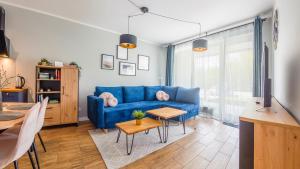 sala de estar con sofá azul y mesa en Apartamenty Sun & Snow Gąski, en Gąski