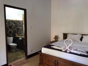a bedroom with a bed with a mirror and a toilet at Cewin's Homestay in Kuta Lombok