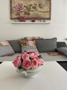 een vaas gevuld met roze rozen zittend op een tafel bij Ferienwohnung Taubertalliebelei in Großrinderfeld