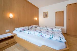 Un pequeño dormitorio con una cama con sábanas azules y blancas. en App Sonne Nr 21, en Lutago