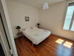 a bedroom with a white bed and a wooden floor at Maison Val de Cher in Noyers-sur-Cher